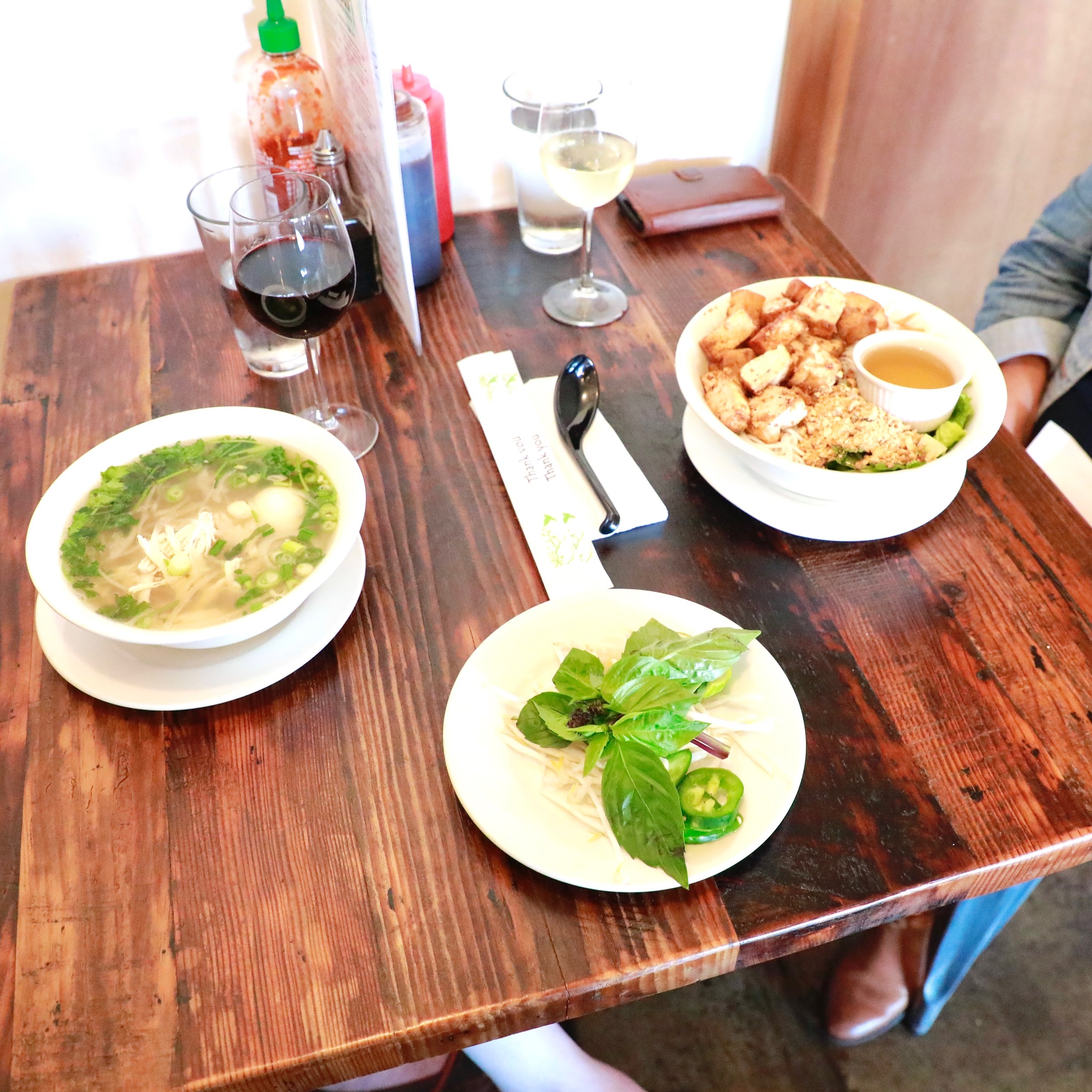 Table spread of phở bowls and Vietnamese sides at La Cà Bar
